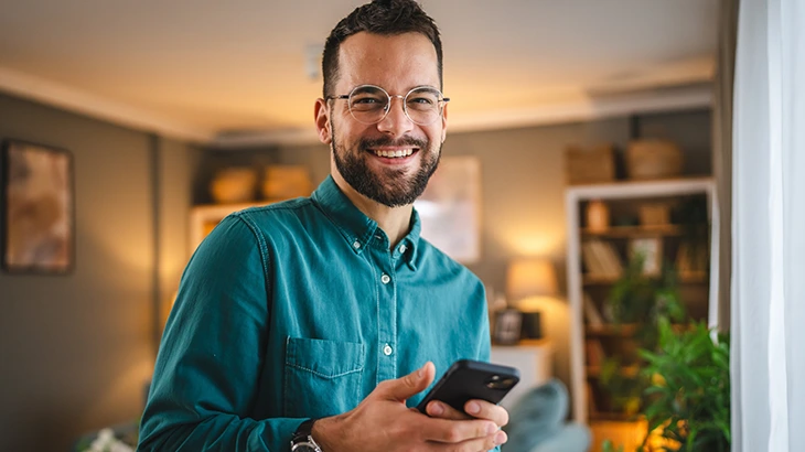 Homem segurando o celular e sorrindo