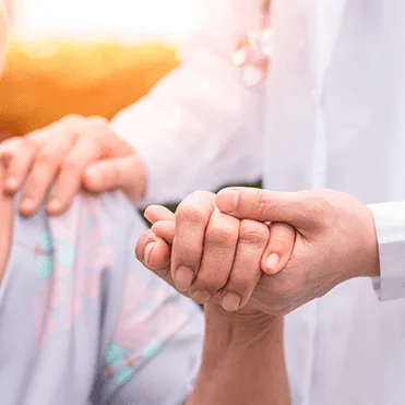 Equipe médica prestando apoio de mãos dadas com paciente