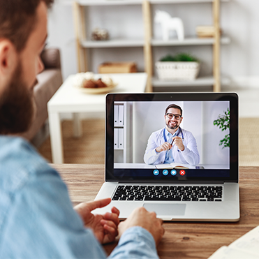 Homem realiza consulta online em casa com notebook