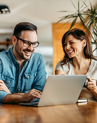 Homem e mulher sorriem enquanto trabalham em um notebook