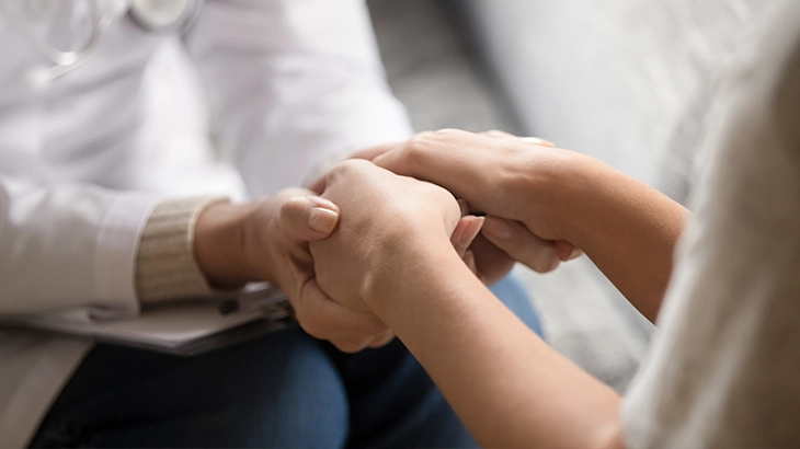 Familia se abraçando feliz no leito de um hospital.